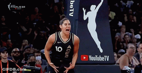 A Female Basketball Player With The Number 10 On Her Jersey Is Screaming In Front Of A Youtube TV Sign . GIF