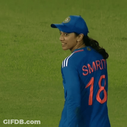 A Female Cricket Player Wearing A Blue Jersey And A Hat Is Walking On A Field . GIF