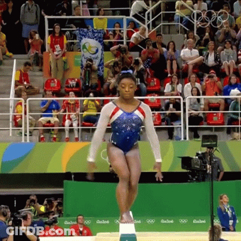 A Female Gymnast Is Doing A Trick On A Balance Beam In Front Of A Crowd At The Rio2016 Olympics GIF