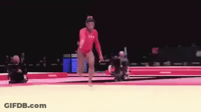 A Female Gymnast Is Doing A Trick On A Mat . GIF