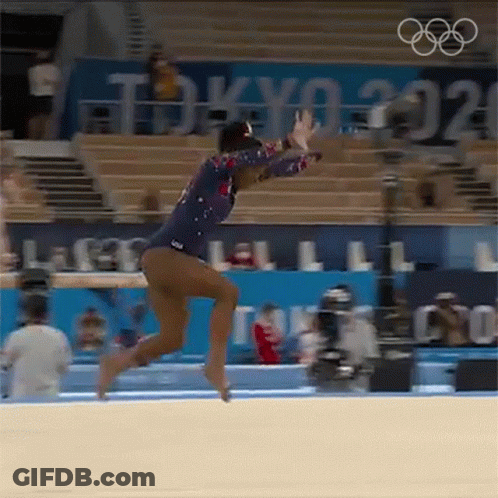 A Female Gymnast Is Doing A Trick On The Floor In Front Of A Crowd At The Olympics . GIF