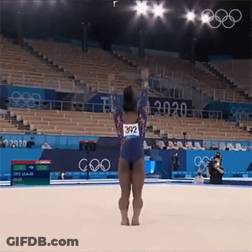 A Female Gymnast Is Doing A Trick On The Floor While Wearing A Number 392 Leotard . GIF