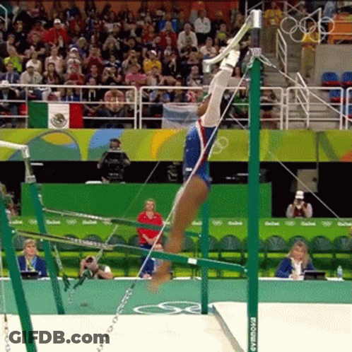 A Female Gymnast Is Doing A Trick On The Uneven Bars While A Crowd Watches . GIF
