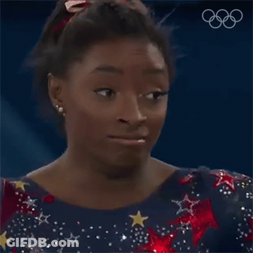 A Female Gymnast Is Making A Funny Face While Wearing A Blue Dress With Stars And A Red Bow In Her Hair . GIF