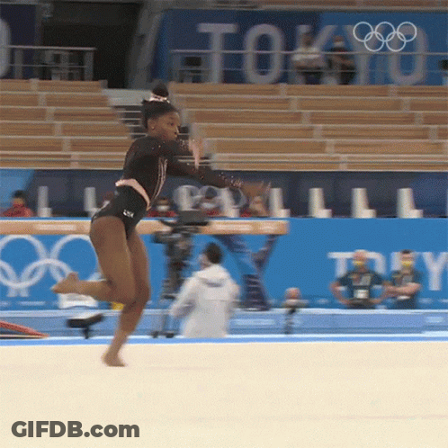 A Female Gymnast Performs On The Floor In Front Of A Sign That Says Tokyo GIF