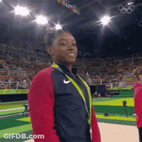 A Female Gymnast Wearing A Nike Jacket And A Medal Around Her Neck GIF