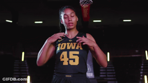 A Female Iowa Basketball Player Stands In Front Of A Basketball Net GIF