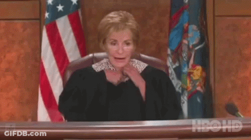 A Female Judge Is Sitting At A Desk In Front Of An American Flag In A Courtroom . GIF