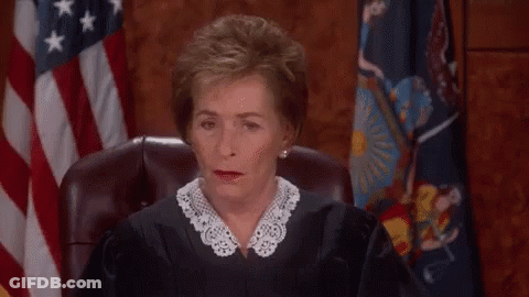 A Female Judge Is Sitting In Front Of An American Flag And Making A Funny Face . GIF