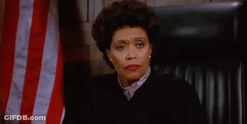 A Female Judge Is Sitting In Front Of An American Flag In A Courtroom . GIF