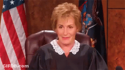 A Female Judge Is Sitting In Front Of An American Flag In A Courtroom . GIF
