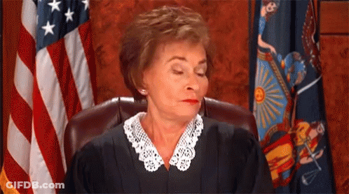 A Female Judge Is Sitting In Front Of An American Flag In A Courtroom . GIF