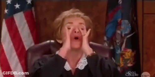 A Female Judge Is Sitting In Front Of An American Flag In A Courtroom . GIF