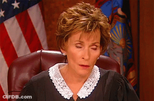 A Female Judge Sitting In Front Of An American Flag GIF