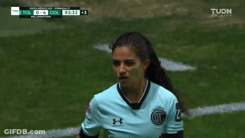A Female Soccer Player Wearing A Blue Under Armour Jersey Stands On A Field GIF
