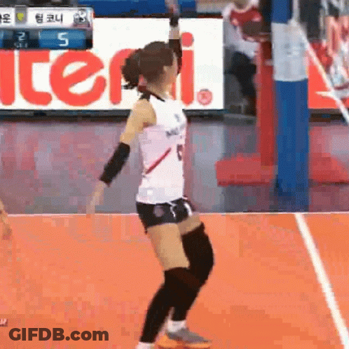 A Female Volleyball Player Is Jumping In The Air On A Court . GIF