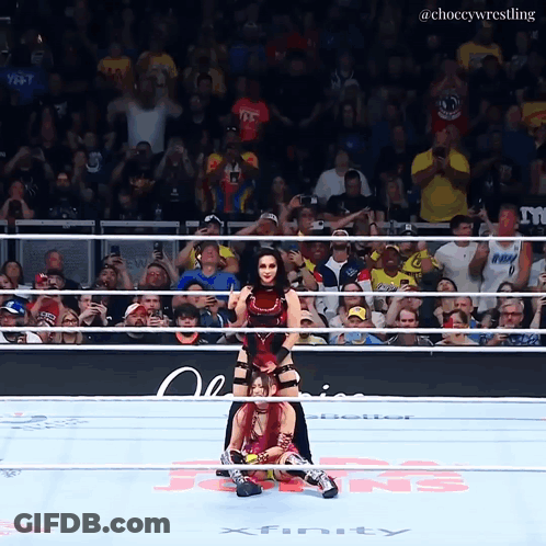 A Female Wrestler Is Being Lifted By Another Wrestler In A Ring That Says Xfinity On The Floor GIF