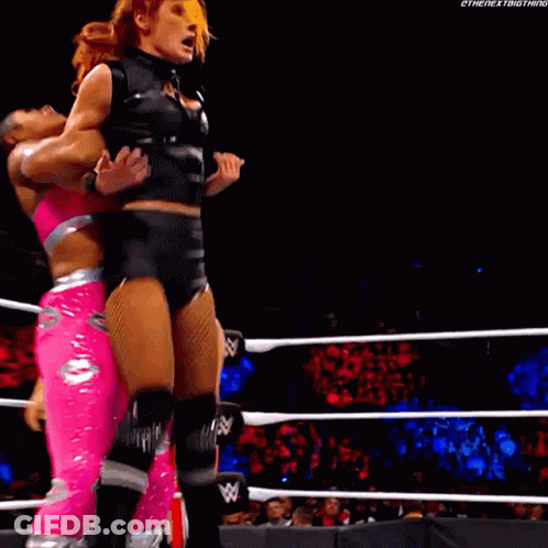 A Female Wrestler Is Being Lifted By Another Wrestler In A Wrestling Ring GIF