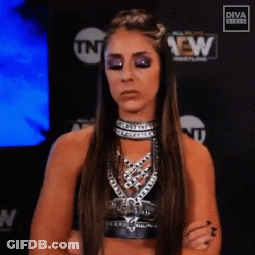 A Female Wrestler Is Standing With Her Arms Crossed In Front Of A Tnt Sign . GIF