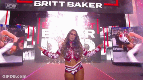 A Female Wrestler Named Britt Baker Is Standing In Front Of A Large Screen GIF