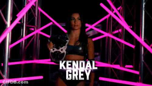 A Female Wrestler Named Kendal Grey Is Standing In A Dark Room With Pink Lights Behind Her GIF