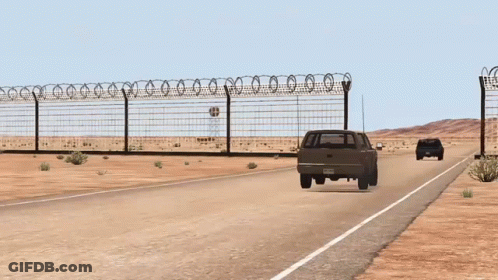 A Fence With Barbed Wire Surrounds A Desert Road GIF