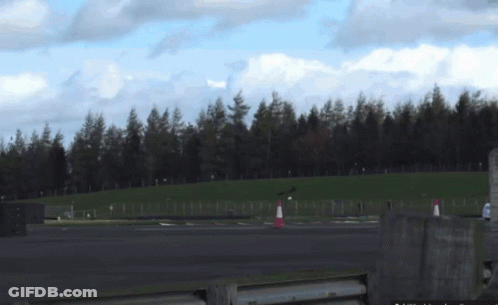 A Fenced In Area With Trees In The Background And A Few Cones GIF