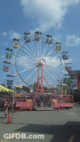A Ferris Wheel At A Carnival With People Riding It GIF