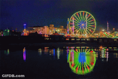 A Ferris Wheel Is Lit Up At A Carnival At Night GIF