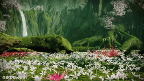 A Field Of Flowers With A Waterfall Behind It GIF