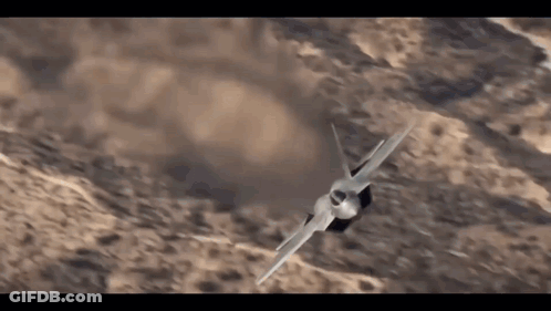 A Fighter Jet Is Flying In The Air Over A Desert Landscape . GIF