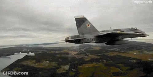 A Fighter Jet Is Flying Over A Landscape With A Large Star On The Tail . GIF