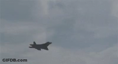 A Fighter Jet Is Flying Through A Cloudy Sky . GIF