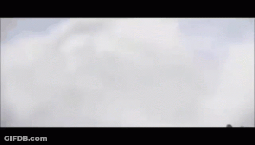 A Fighter Jet Is Flying Through A Cloudy Sky . GIF