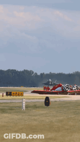 A Fighter Jet Takes Off From A Runway With Trees In The Background GIF