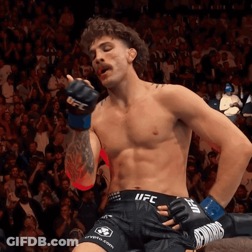 A Fighter Wearing Shorts That Say UFC Is Standing In Front Of A Crowd GIF