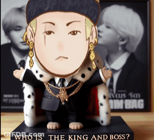 A Figurine Of A Man In A Suit And A Crown Is Sitting On A Book Titled Who Is The King And Boss GIF