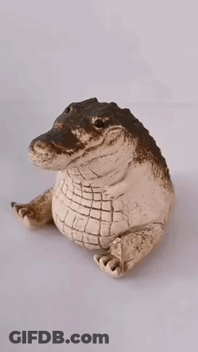 A Figurine Of An Alligator Wearing A Gold Crown GIF
