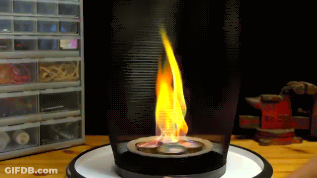 A Fire Is Burning In A Glass Container On A Table In Front Of A Toolbox That Says ' Bosch ' On It GIF
