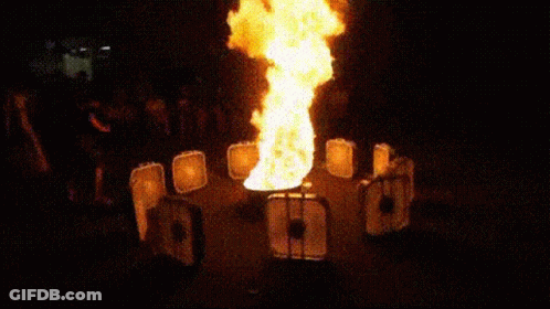 A Fire Is Coming Out Of A Container In A Dark Room . GIF