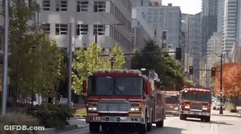 A Fire Truck With The Letter L On The Front Is Driving Down The Street GIF