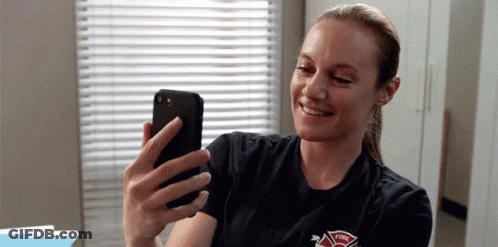 A Firefighter Is Taking A Selfie With Her Cell Phone . GIF