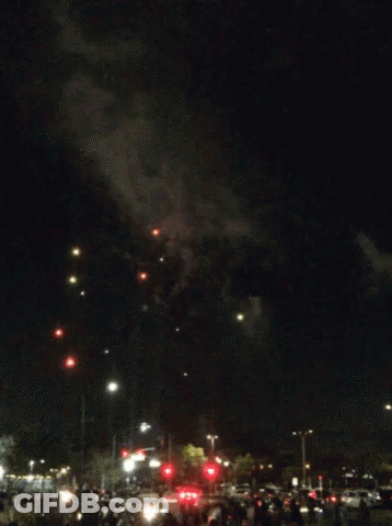 A Fireworks Display In A Parking Lot With A Crowd Watching GIF