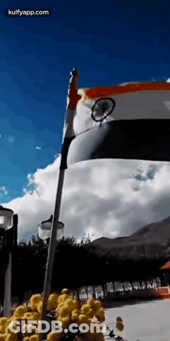 A Flag Is Waving In The Wind In Front Of A Blue Sky . GIF