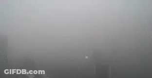 A Foggy City Skyline With A Lot Of Smoke Coming Out Of A Window . GIF