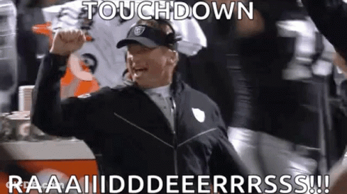 A Football Coach Is Raising His Fist In The Air While A Group Of Players Celebrate A Touchdown . GIF