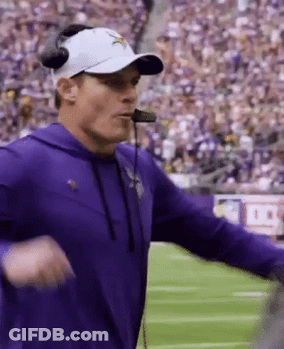 A Football Coach Wearing A Purple Shirt And A White Hat GIF