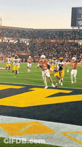 A Football Game Is Being Played In A Stadium With A Large M On The Field GIF