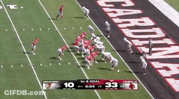 A Football Game Is Being Played On A Field With A Banner That Says Cardinals On It . GIF