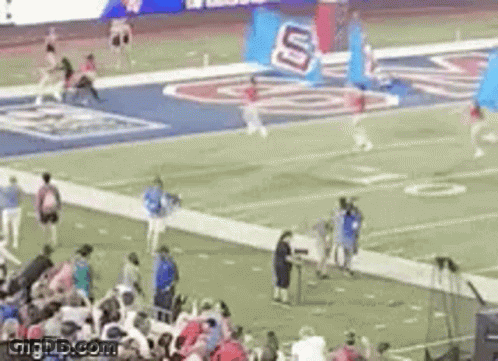 A Football Game Is Being Played On A Field With A Crowd Of People Watching . GIF
